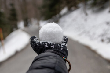 Mão com luvas no inverno segurando bola de neve.
