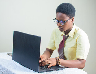 Female African with glasses and beads on her wrist, using laptop or computer by typing on the keyboard