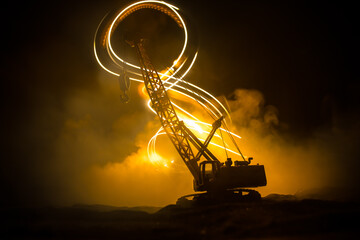 Abstract Industrial background with construction crane silhouette over amazing night sky with fog and backlight. Tower crane against the foggy sky at night.