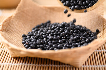 Black soybean seeds pouring in basket, Food ingredients