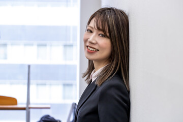 壁に寄りかかり笑顔の女性