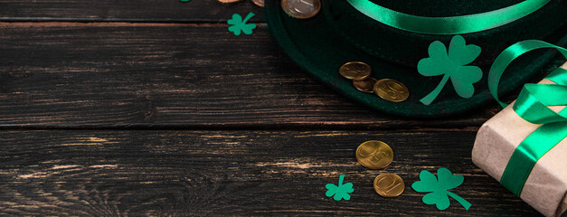 Leprechaun hat and shamrock clover leaves on brown wooden background. Happy St. Patrick's Day.