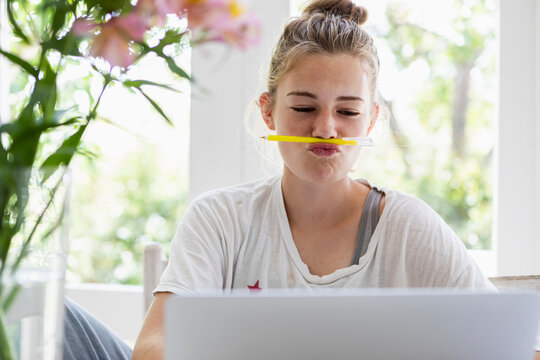 Girl (16-17) using laptop at home