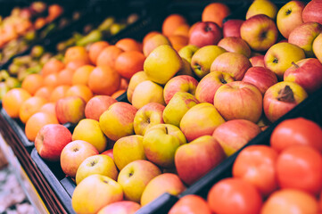 Close-up, red apples on the counters. Against the background of oranges and tangerines in the supermarket.