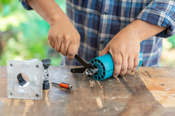 Man change cutting head of electric router in carpenter workshop.