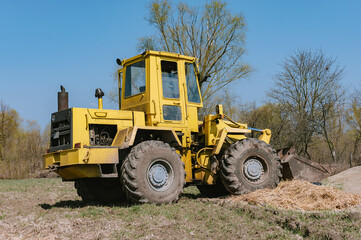 Fototapeta na wymiar Yellow wheel loader excavator. Against the background of the field.