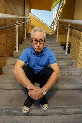 Scared expression old man sitting on a staircase