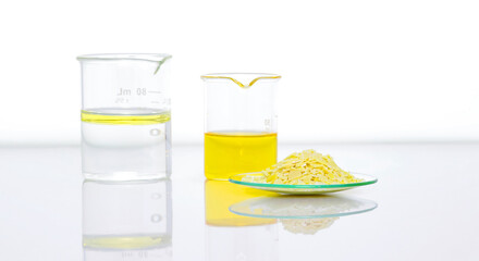 Closeup chemical ingredient on white laboratory table. Sodium sulfide flake in Chemical Watch Glass place next to Aluminium chloride liquid, oil and alcohol in Beaker. Side View