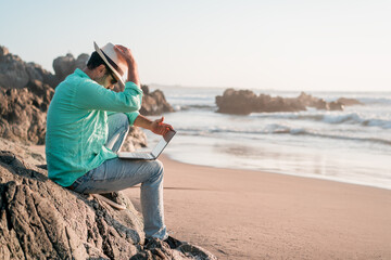 man sitting with a laptop alone at the beach