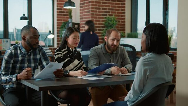 Female applicant attending job interview appointment, giving cv files to group of businesspeople at employment meeting. Team of employees analyzing resume of candidate for company recruitment.