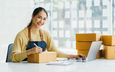 Starting Small business entrepreneur SME freelance,Portrait young woman working at home office, BOX,smartphone,laptop, online, marketing, packaging, delivery, SME, e-commerce concept