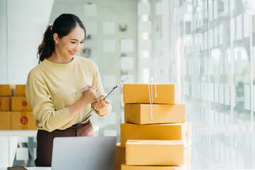 Young asia seller woman happy work on laptop busy cellphone call chat to customer at home office...