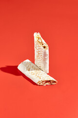 Shawarma wrap with beef on color background with hard shadow. Beef shawarma sandwich in abstract...