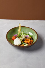 Salad bowl with salmon, avocado, broccoli, vegetables and egg on homemade ceramic plate. Buddha bowl with salmon, broccoli, quinoa in modern serveware. Modern ceramic dishware on concrete background.