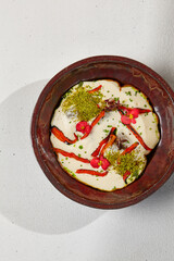 Carrot soup with creamy espuma in dark ceramic bowl. Vegetable cream soup in modern dishware with hard shadow.