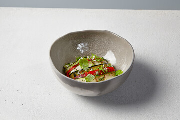 Vegetable ratatouille with zucchini, eggplant and paprika on summer style with hard shadow. Baked vegetables in handmade ceramic bowl. Summer food in modern dishware.