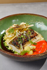 Halibut fillet with bulgur, grilled cauliflower and tomato sauce. Cooked fish fillet with garnish...