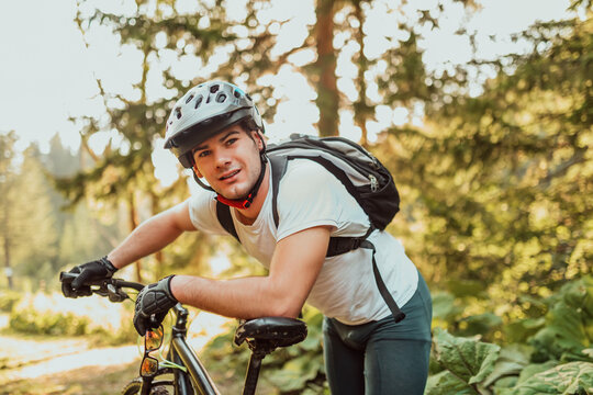 Tired bicyclist in sport clothes and helmet taking break after outdoors training. Healthy caucasian man spending free time for workout on fresh air.
