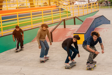 Group of young skaters sliding to jump on a ramp in a skate park