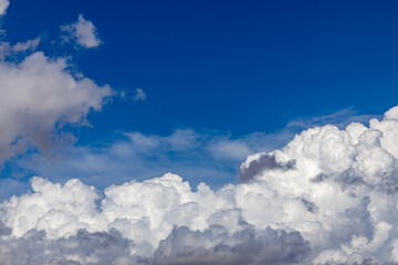 Naklejka na ściany i meble thick white cummulus clouds on a sunny day against a bright blue sky. absorbent cotton clouds indicating bad weather. blue background on a sunny day. 