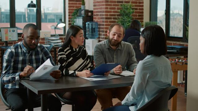 Multiethnic team of HR people interviewing job candidate, analyzing cv resume and talking about recruitment. Woman meeting with group of businesspeople to discuss about executive job.