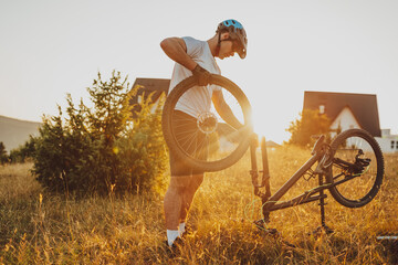 The cyclist repairs and changes the tire on his bike to the mountain at sunset. Bicycle tire repair. Selective focus