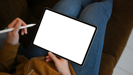 Relaxed young female using digital tablet touchpad on sofa at home.