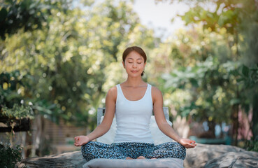Young woman practicing yoga in the nature .Yoga is meditation and healthy sport concept with green nature background.