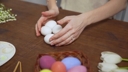 Close-up on a table with items to create a composition for Easter. Women's hands arrange objects on...