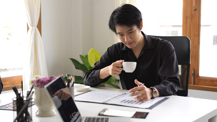 Businessman sipping coffee while looking at the financial data