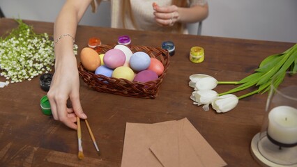 Close-up on a table with items to create a composition for Easter. Women's hands arrange objects on...