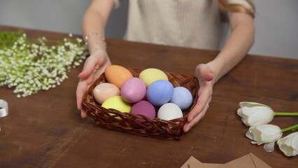 Close-up on a table with items to create a composition for Easter. Women's hands arrange objects on...