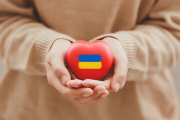 The concept of ending the war in Ukraine. Women's Hands holding the heart of Ukraine. No war. The concept of participation of the Ukrainian people in the war with Russia. Stop Putin
