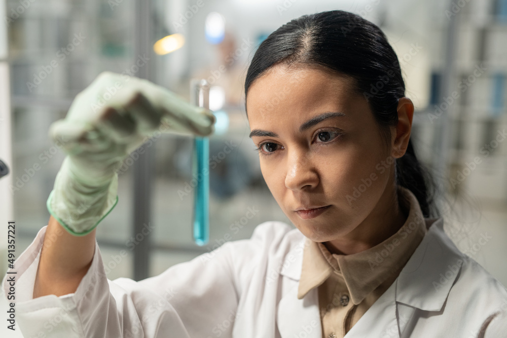 Aufkleber contemporary scientist looking at flask with blue liquid substance during scientific experiment in c