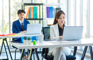 Asian young professional successful female businesswoman manager in white formal suit standing helping mentoring new recruitment businessman sitting working with laptop computer in company office