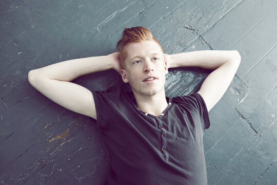 Lost In A Day Dream. A Red Haired Male Lying On The Floor And Looking Upwards With A Thoughtful Look On His Face.