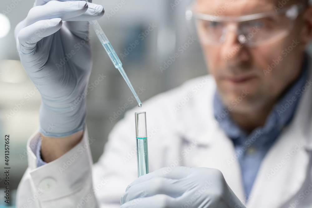 Poster Serious scientist with flask and pipette making experiment with liquid substance while adding some drops of antidote