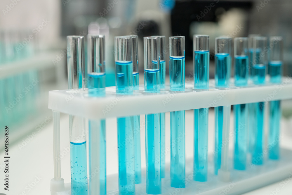 Poster row of several flasks or test tubes with blue liquid on workplace of modern healthcare worker or sci