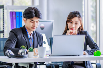 Asian young happy professional male businessman mentor and female businesswoman colleague in formal suit working discussing meeting together at workplace desk with laptop notebook computer in office