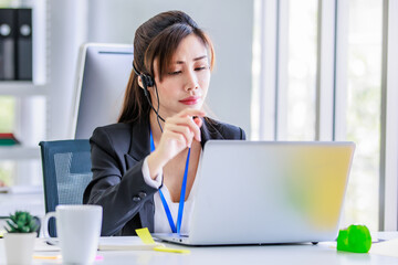 Asian young beautiful female businesswoman operator wearing headset with microphone working at helpdesk service laptop computer helping consulting with customers call center