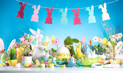 Easter time. Easter decorations on the rustic wooden table. Easter bunny, easter eggs in basket and cabbage leaf. Blue background.