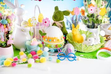 Easter time. Easter decorations on the rustic wooden table. Easter bunny, easter eggs in basket and cabbage leaf. Blue background.