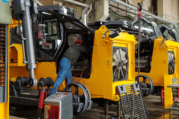 Engineer of modern industrial or construction plant examining motor of huge machine in hangar or workshop before repairing it