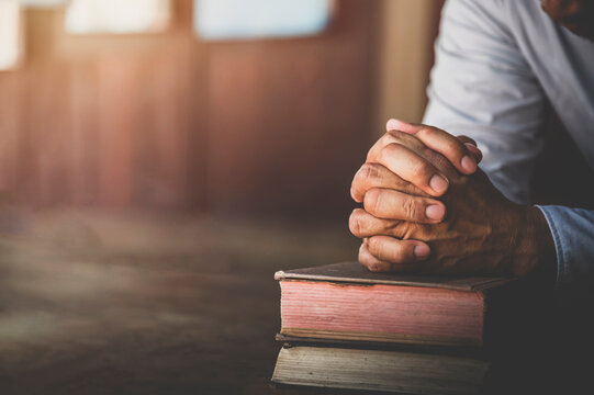 Hands of a man pray on bible, hope, faith, christianity, religion concept.