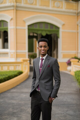 Portrait of handsome young African businessman outdoors