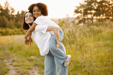 Fototapeta premium Caucasian mother holding her mixed race daughter on her back