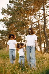 Fototapeta premium Caucasian mother and two her mixed race daughters walking in a park