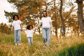 Fototapeta premium Caucasian mother and two her mixed race daughters walking in a park
