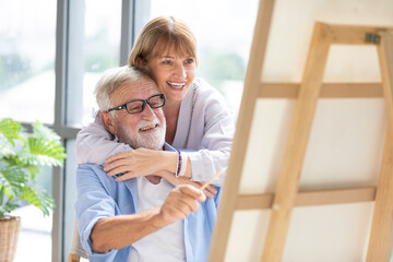 senior couple looking to painting on a canvas in free time