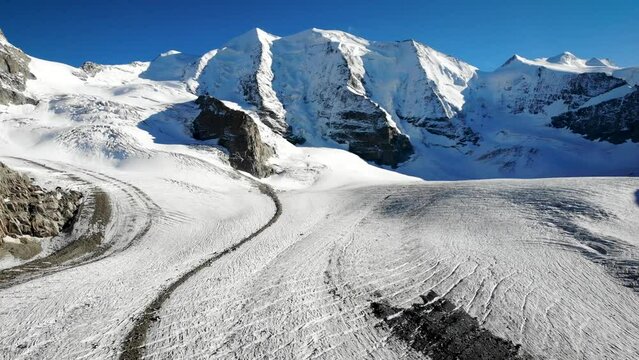Aerial flyover over Pers glacier near Diavolezza in Engadin Switzerland with a pan down from the Piz Bernina peak down to the crevasses